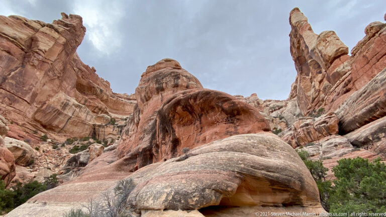 A smooth sandstone dome rises toward a small opening below a rounded tower and narrow spire.