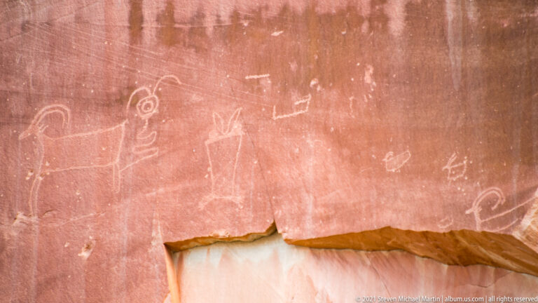 Pale looped and angular markings appear on a close-cropped red sandstone wall.