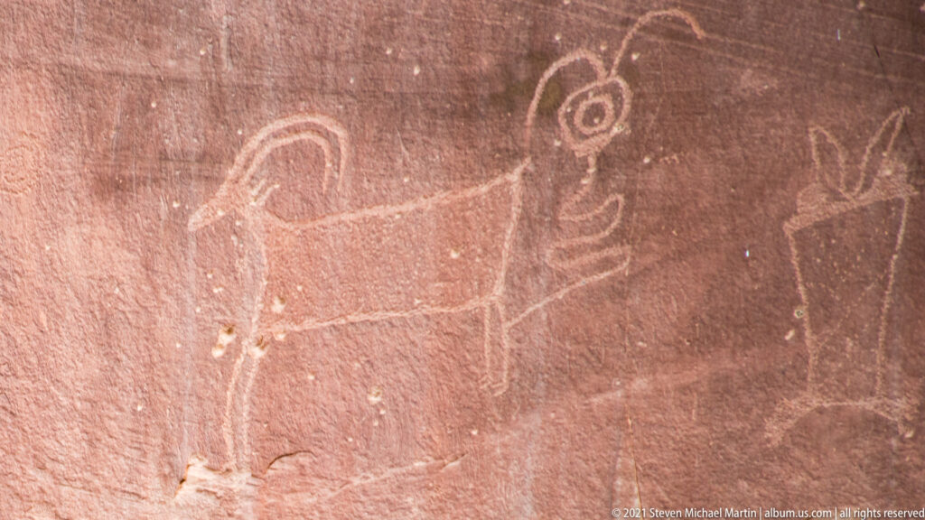 A large outlined figure and smaller markings cover a red sandstone wall.