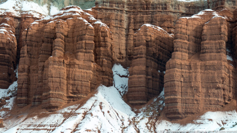 Tall banded sandstone ribs fill the frame, with snow lodged between the rounded columns.