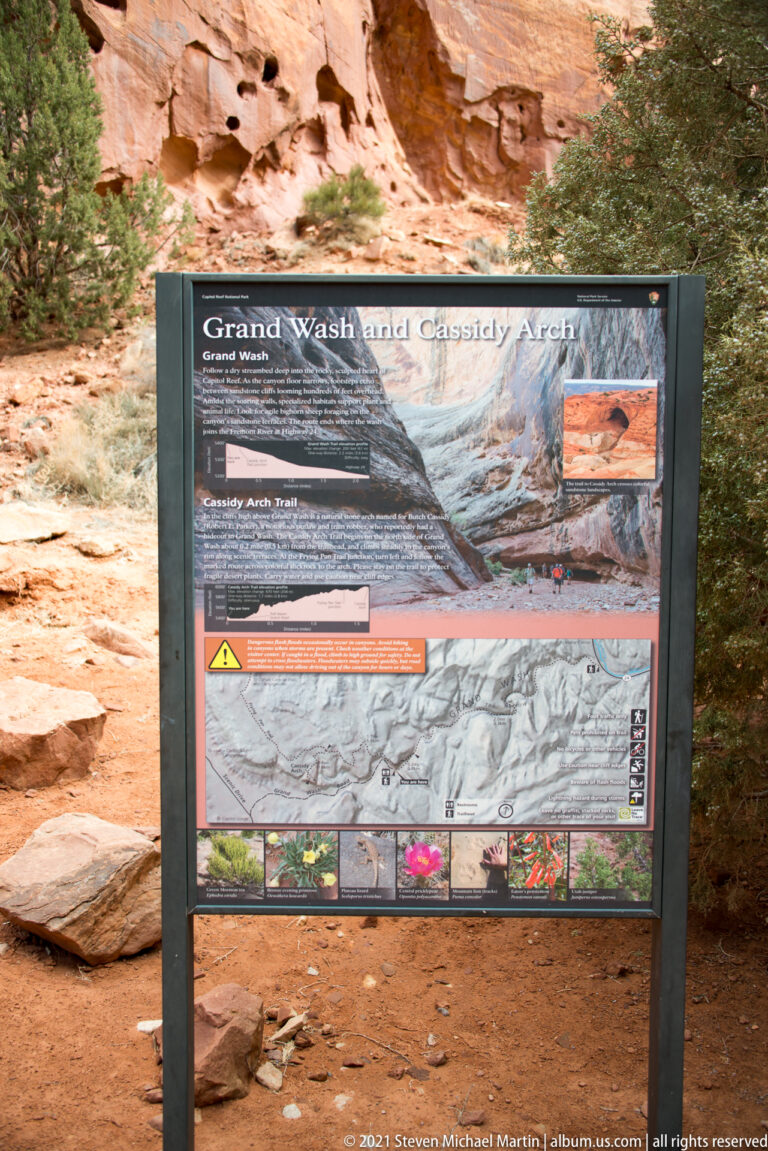 Interpretive panel titled “Grand Wash and Cassidy Arch,” with a canyon photo, trail map and warning strip.