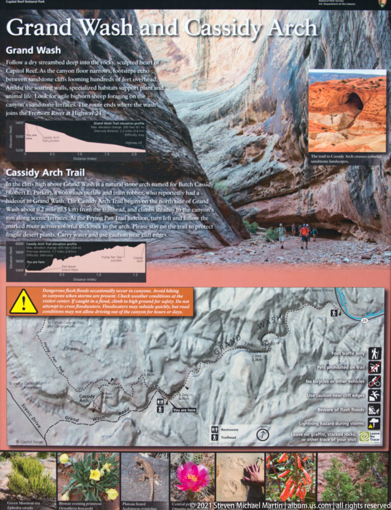 Close view of the Cassidy Arch Trail sign, showing route profiles, an inset arch photo, map and safety strip.