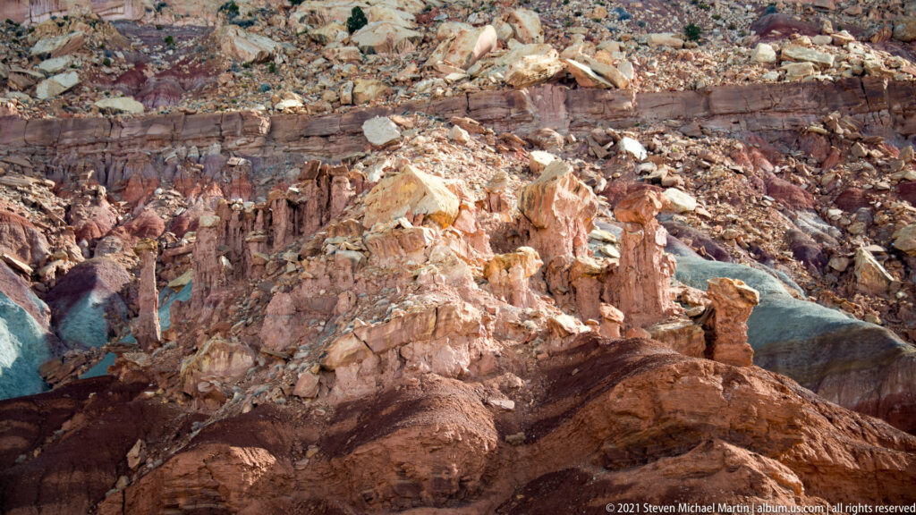 Angular sandstone blocks and rubble lie above a dark horizontal band of exposed rock.