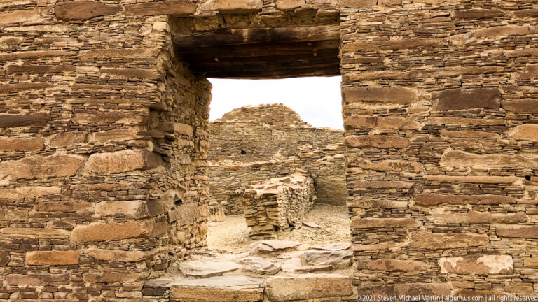 A stone doorway with a heavy lintel frames a second masonry room beyond.