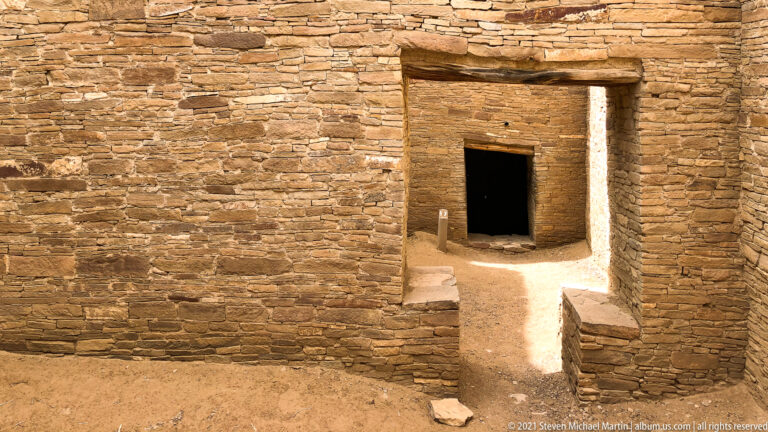 A stone doorway with a broad lintel leads to a second shadowed opening between low ledges.