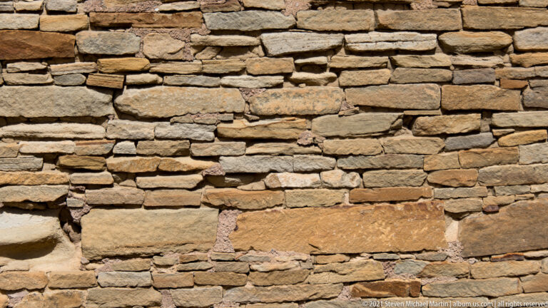 Closely stacked horizontal sandstone courses fill the frame, with uneven edges and warm color variation.