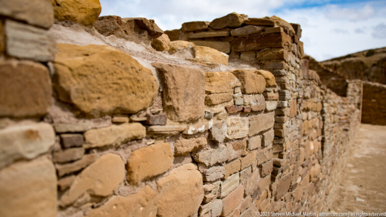 Large sandstone blocks line a wall that recedes toward a taller corner in oblique perspective.
