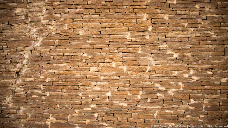 Closely fitted horizontal sandstone blocks and smaller chinking stones fill the frame.