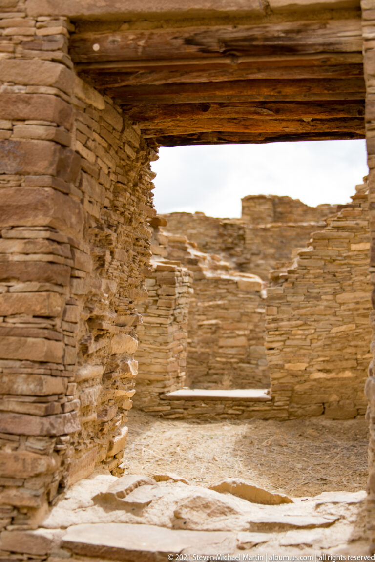 A rectangular doorway through thick stone walls opens onto a bright interior courtyard.