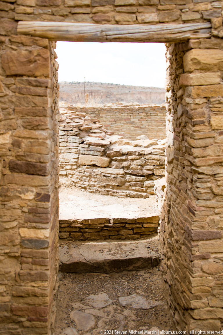 A stone doorway frames low steps and another wall, with layered lintels spanning the opening.