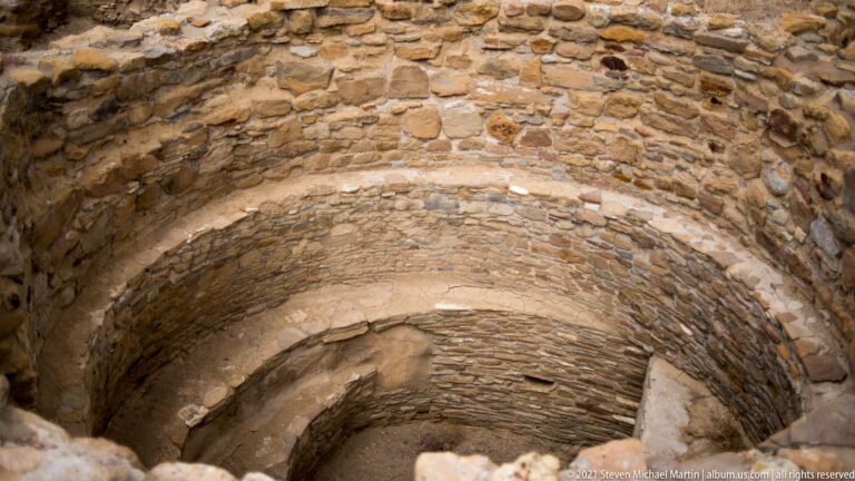 A deep round stone chamber descends beneath an irregular rim into a shadowed interior.