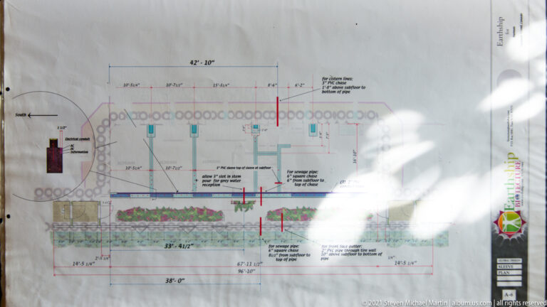 A long house plan shows divided rooms, doorways, dimensions, a planted strip, and a circular outer wall.