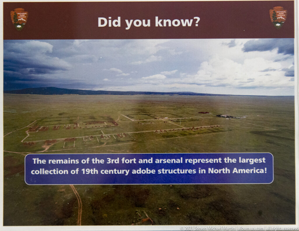 An aerial view shows a large grid of adobe ruins and foundations across open prairie.