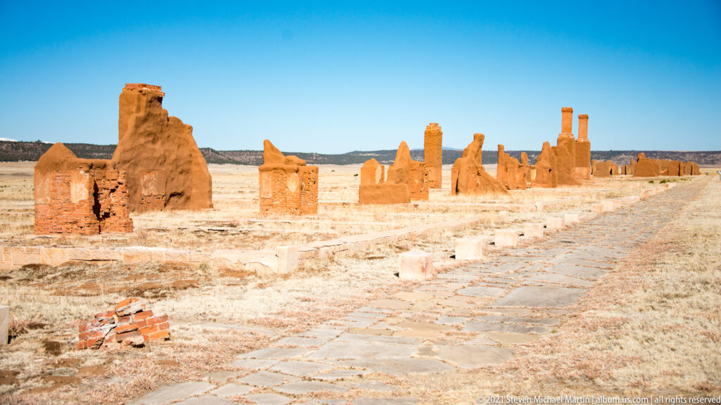 Stone path runs beside a long diagonal line of adobe ruins and foundations.