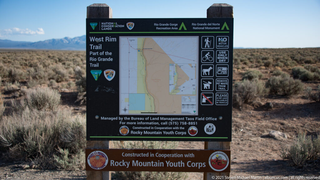 A black West Rim Trail sign shows a map and icons for permitted and prohibited uses.