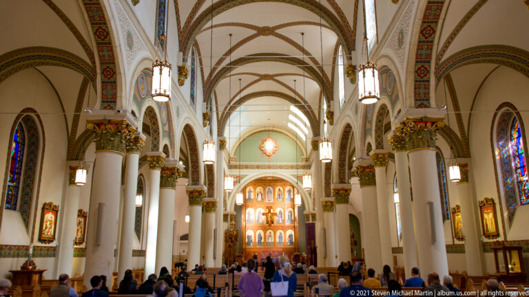 The cathedral nave leads toward a gilded altar beneath vaulted arches and stained-glass windows.