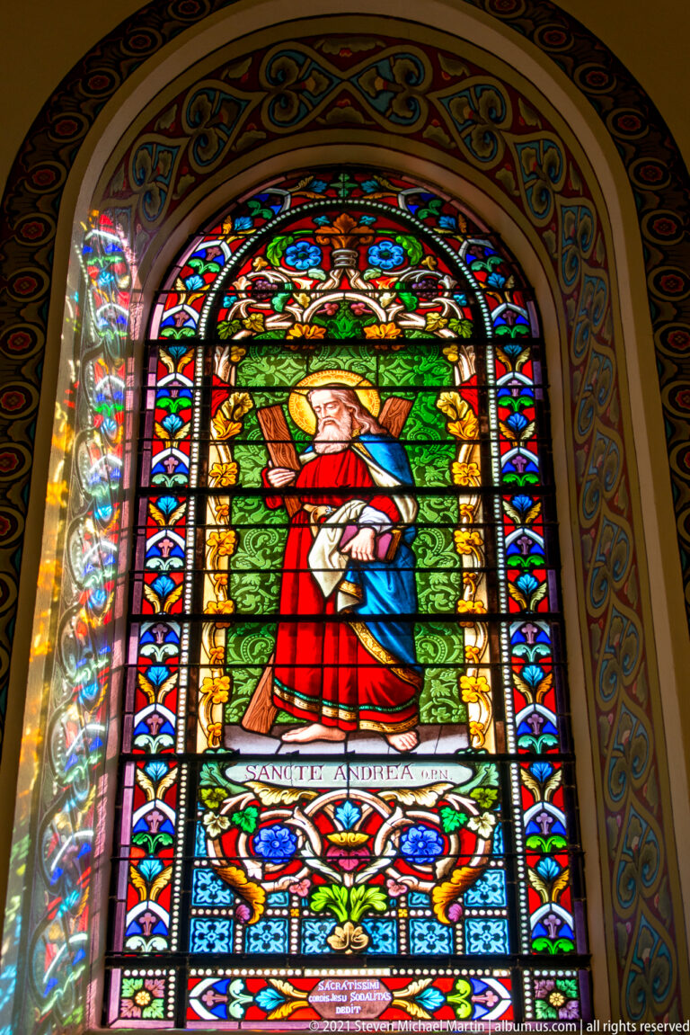 A stained-glass portrait labeled “Sanctus Andreas” shows a haloed saint holding a diagonal cross.
