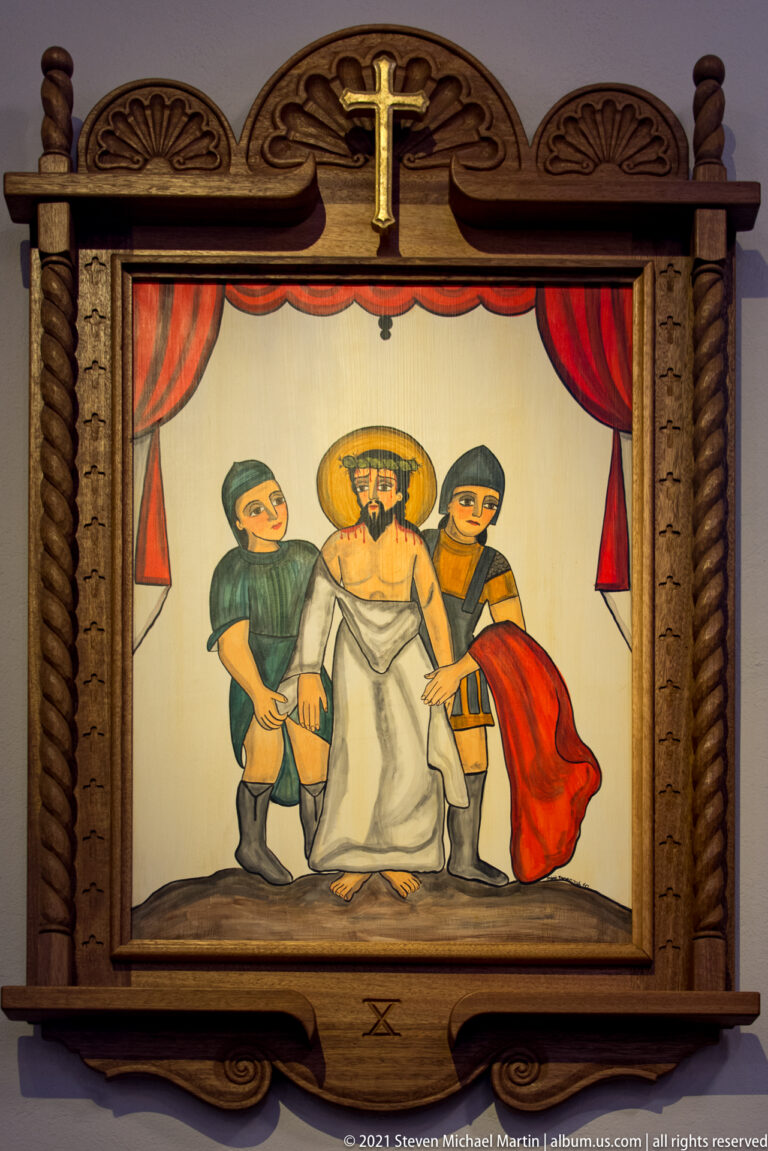 Framed religious painting shows Christ between two men beside a cross, with Roman numeral X below.