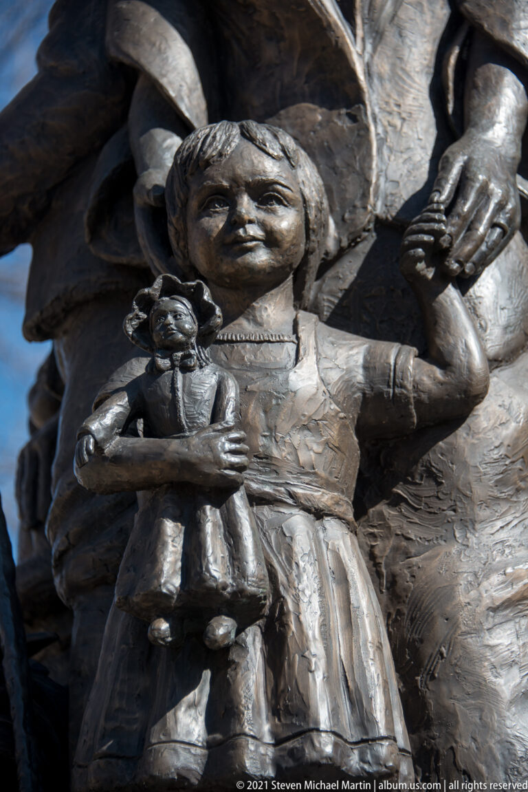 Bronze woman cradles a child in a close view framed by larger sculptural forms.