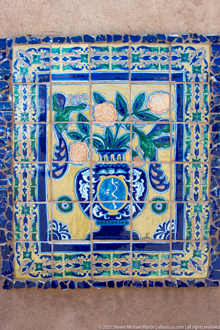 Blue and yellow glazed tiles form a floral panel with stylized birds and patterned borders.