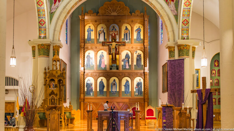 Gilded reredos with painted figures and a central crucifix behind the altar and lectern.
