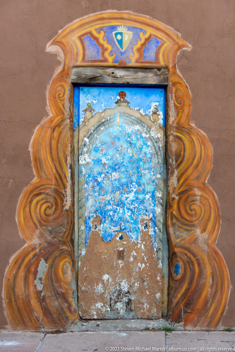 Weathered blue image inside a rectangular wall niche framed by swirling orange and ochre paint.