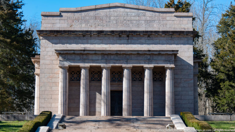 Tall stone columns support an engraved dedication above the memorial entrance and upper steps.