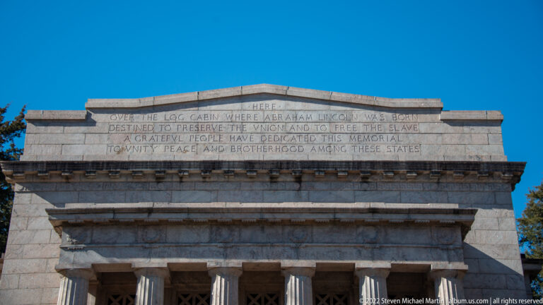 A carved dedication about Lincoln’s birthplace and national unity spans the stone band above the columns.
