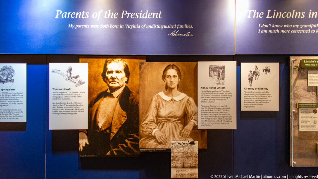 Portraits of Abraham Lincoln and Nancy Hanks Lincoln appear among biographical panels on a blue exhibit wall.