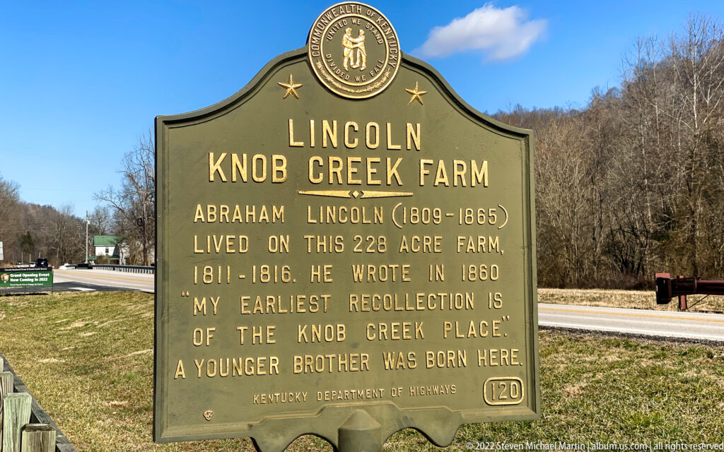 A bronze roadside marker describes Lincoln’s years at Knob Creek beside a road and wooded hillside.