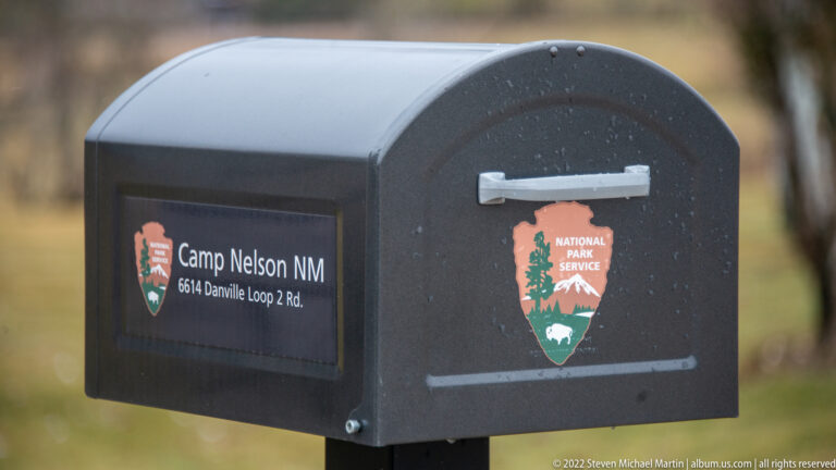 A black mailbox marked “Camp Nelson NM” and the National Park Service arrowhead stands outdoors.