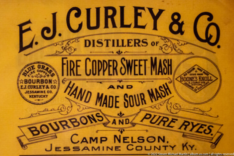 An ornate yellow whiskey label names E. J. Curley and Camp Nelson, Jessamine County, Kentucky.