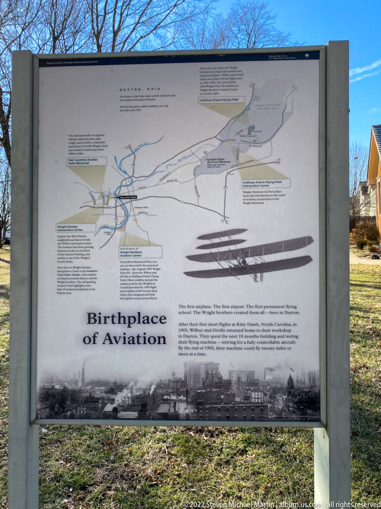 A Birthplace of Aviation wayside panel displays a Dayton-area map and aircraft silhouettes beside a grassy path.