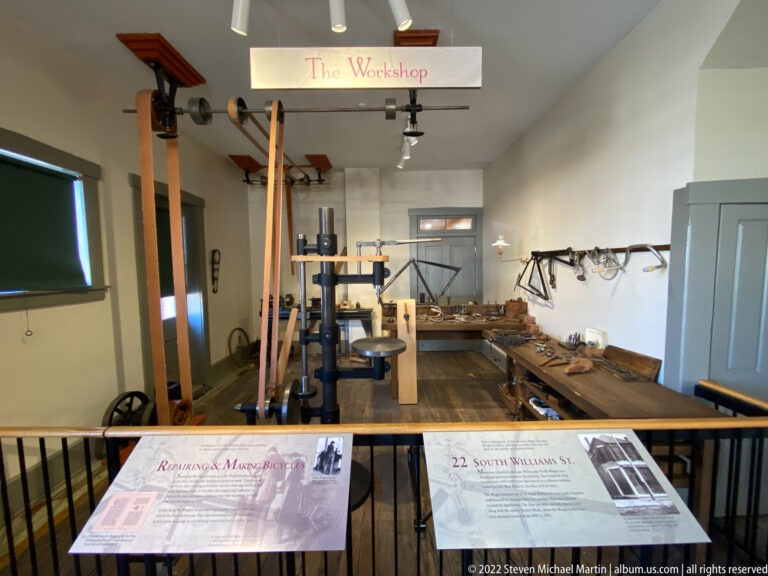 A room labeled The Workshop contains workbenches, tools, and bicycle frames along the back wall.