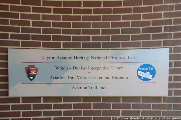 A plaque on a brick wall names the Wright–Dunbar Interpretive Center and Aviation Trail Visitor Center and Museum.