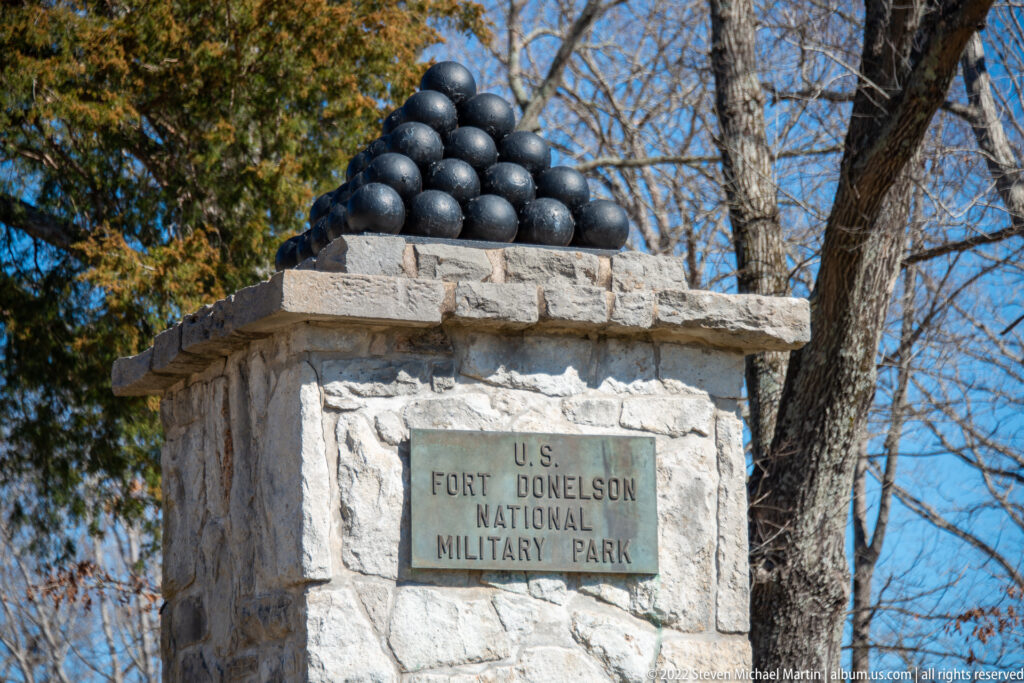 A stone pillar topped with cannonballs bears a plaque naming U.S. Fort Donelson National Military Park.