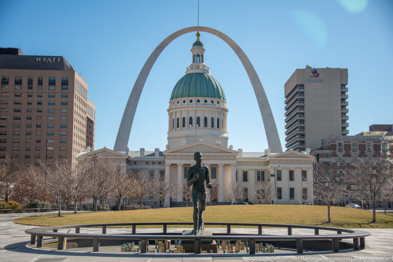 A standing statue and the Old Courthouse align with the Gateway Arch in the background.