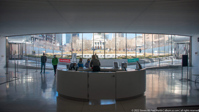 A curved information desk sits before a glass wall overlooking the city.