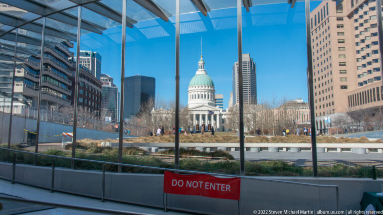 The Old Courthouse is seen through glass above a red restricted-area barrier.