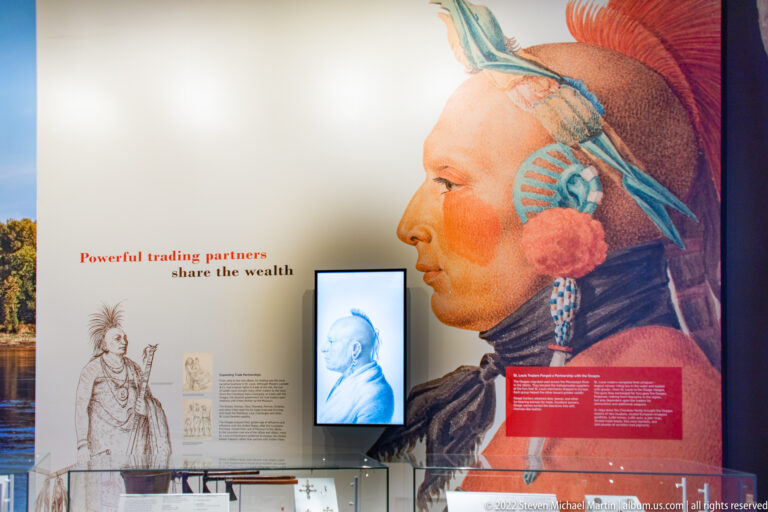 A painted profile of a Native American man appears beside text about trading partners and smaller exhibit images.