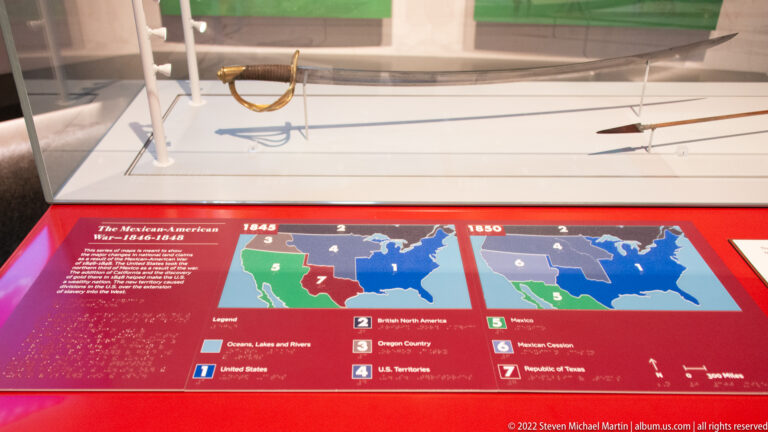 Maps labeled 1845 and 1846 sit beneath a case of objects in a Mexican-American War exhibit.