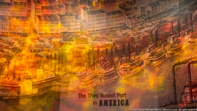 A riverfront mural shows boats and dense city buildings beneath the caption “The Third Busiest Port in America.”