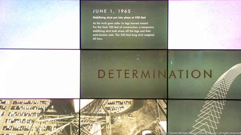 A construction exhibit panel dated June 1, 1965, describes a stabilizing strut, with an aerial worksite image below.