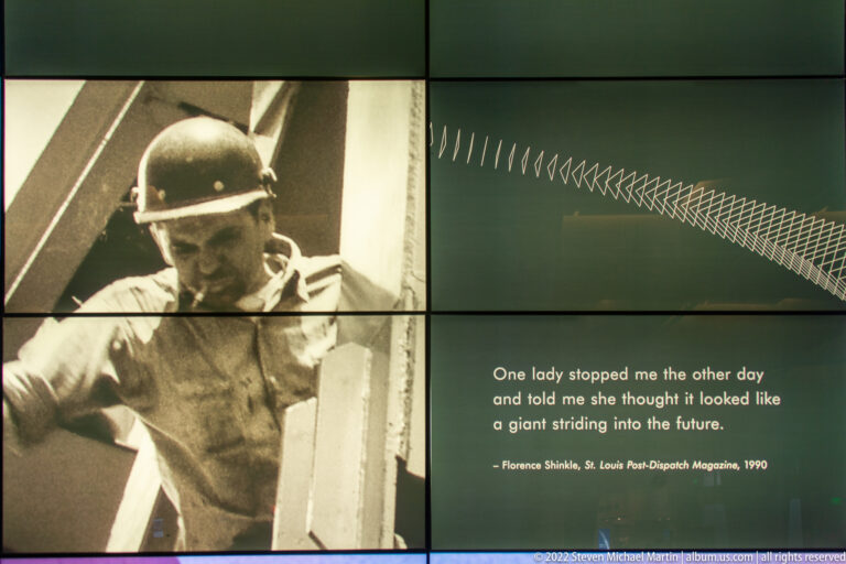 A worker portrait and a quotation about the Gateway Arch appear side by side on a tiled exhibit wall.