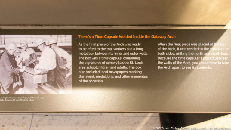 A time-capsule exhibit panel pairs a photograph of workers with text about a capsule sealed inside the Gateway Arch.