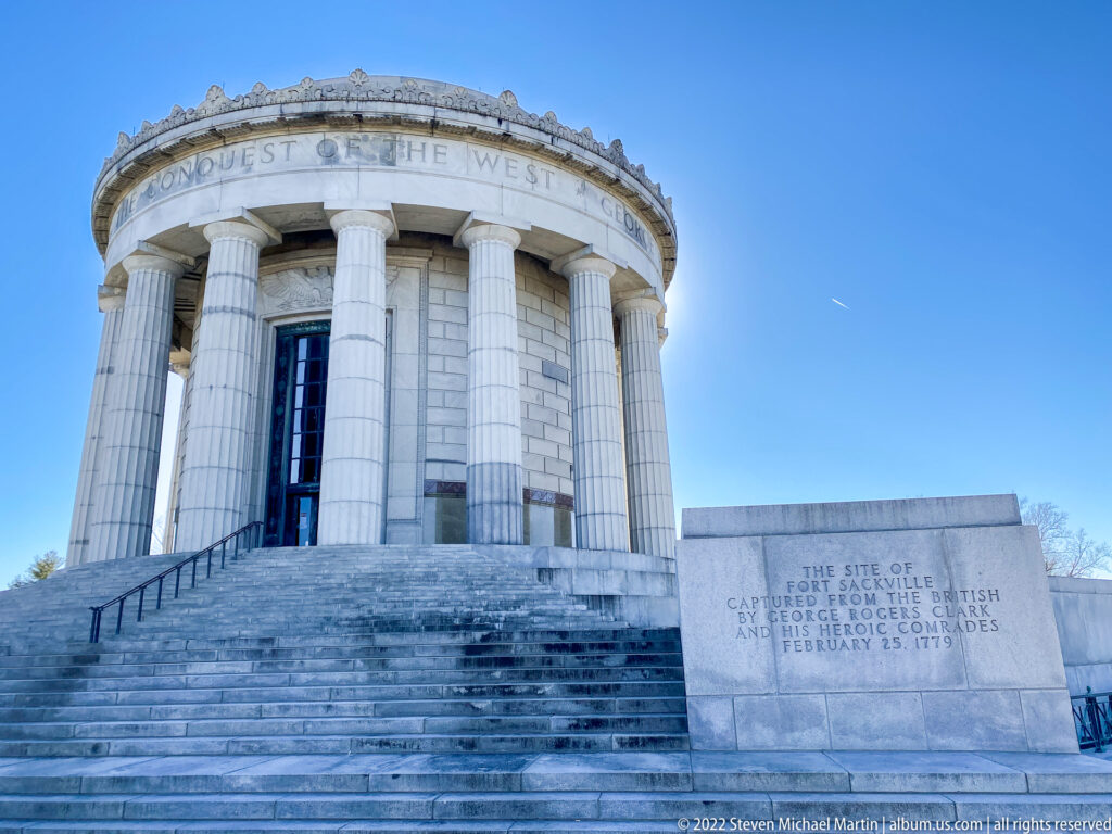 Stone steps lead to the columned memorial beside a panel about Fort Sackville’s capture.