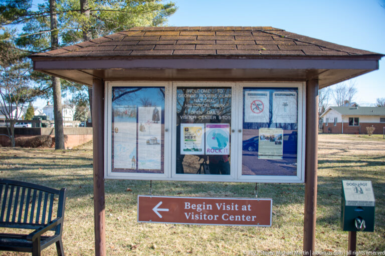 A park information kiosk stands above a sign pointing toward the visitor center.