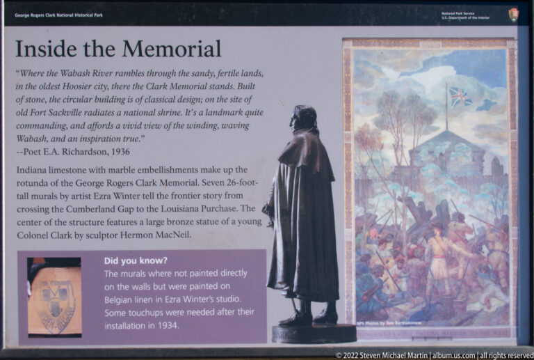 A visitor stands beside a history panel and large mural about the memorial.