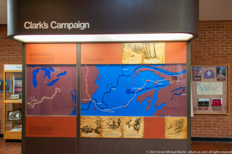 A large blue regional map with route lines fills a gallery wall above historical images.