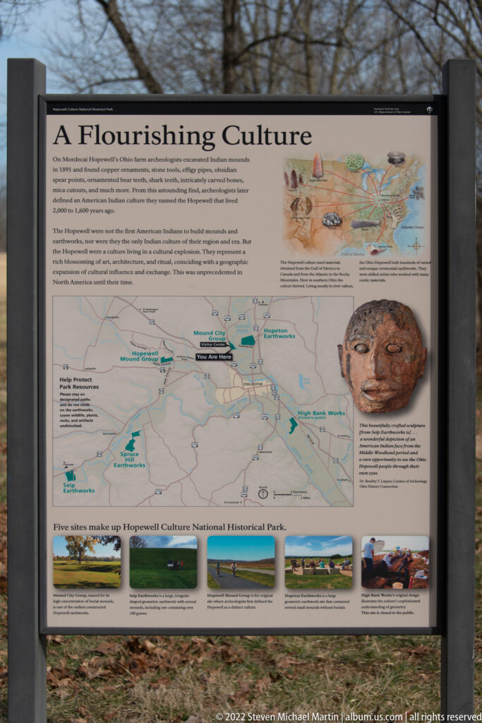 A glass-covered wayside panel shows a regional map, artifact image, and landscape photographs.